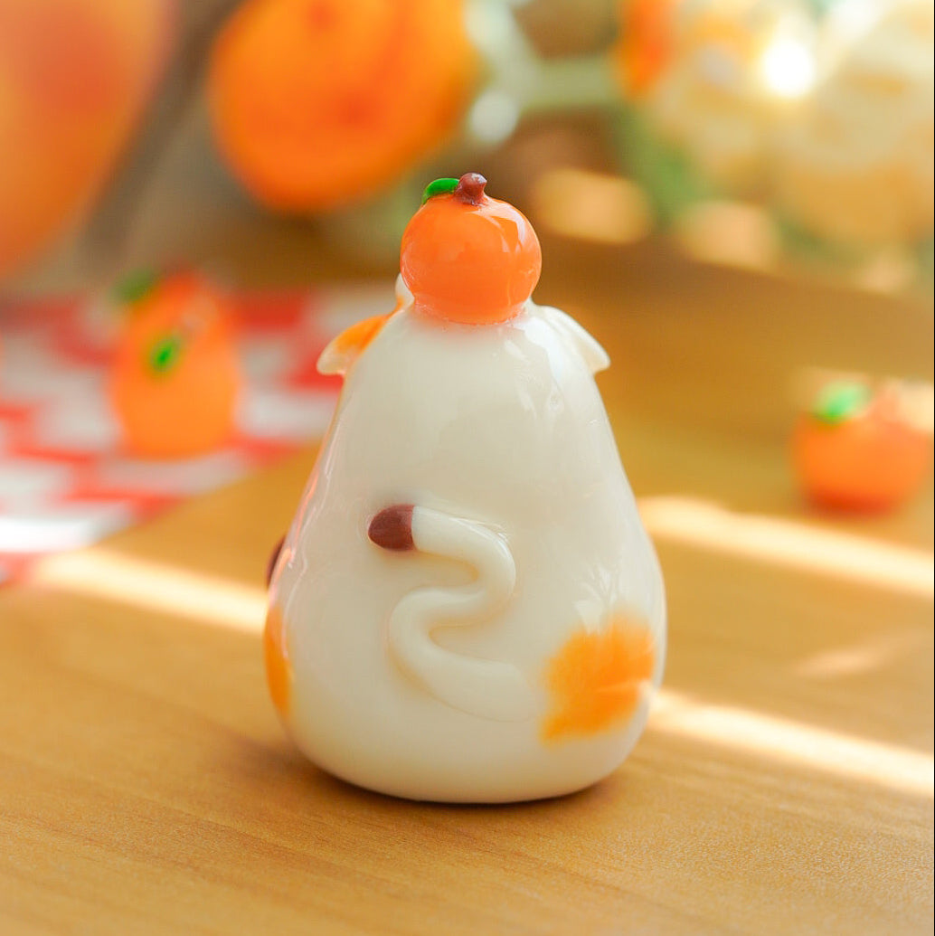 A small white decorative cow figurine kawaii fruit, decorated with orange accents and a small peach, standing on a wooden surface with a softly blurred warm background.