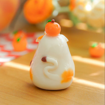 A small white decorative cow figurine kawaii fruit, decorated with orange accents and a small peach, standing on a wooden surface with a softly blurred warm background.
